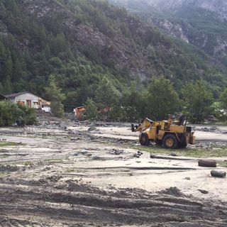 Nell'immagine di repertorio, uno scavatore impegnato nel ripristino di un'area inondata a Ollomont