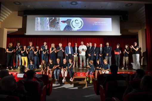 Al centro il regista vincitore del 27° Stambecco d'Oro, Yann Sochaczewski, con intorno le autorità presenti, il team di Fondation Grand Paradis e i bambini della scuola primaria di Cogne
