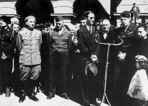 Alessandro Passerin d'Entrèves (quarto da sinistra), Prefetto C.L.N. d'Aosta, assiste, assieme ad altre personalità valdostane ed alleate, alla sfilata partigiana