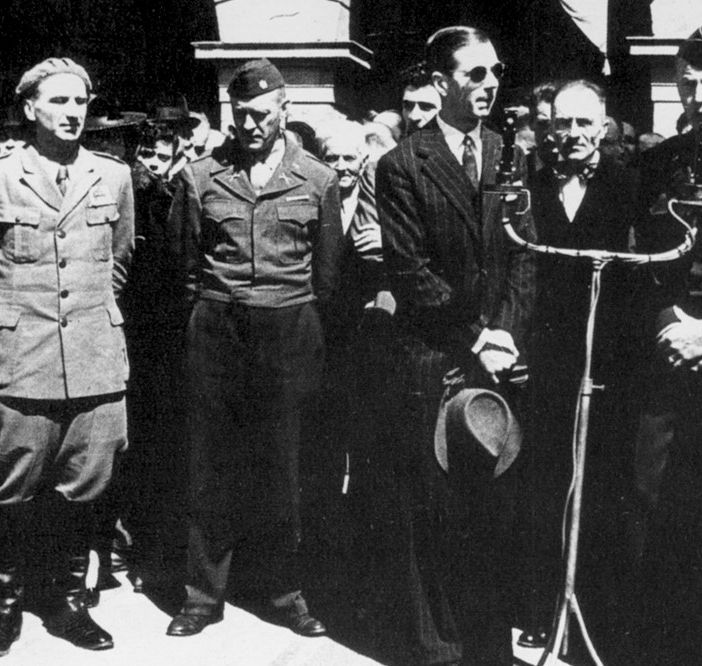 Alessandro Passerin d'Entrèves (quarto da sinistra), Prefetto Cln d'Aosta, assiste, assieme ad altre personalità valdostane ed alleate, alla sfilata partigiana