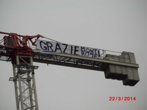 Lo striscione appeso al vertice della gru. In basso, la struttura posizionata al di fuori dello spazio di cantiere,in un'area privata Lo striscione appeso al vertice della gru. In basso, la struttura posizionata al di fuori dello spazio di cantiere,in un'area privata
