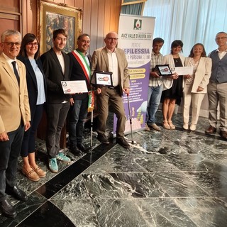 l’Assessore regionale ai Trasporti Luigi Bertschy, l’Assessora al Turismo di Doues Corinne Cuaz, il Vice Sindaco di Doues Daniel Diemoz, il Sindaco di Doues Giorgio Abram, il Presidente della Regione Renzo Testolin, i genitori della minore di Doues, la Coordinatrice l’istituzione scolastica Grand Combin Simona d’Agostino, il Presidente di AICE Valle d’Aosta ODV Manuele Amateis